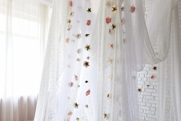 Baldachin on bed. Summer pink peonies and roses flowers levitating, hanging flowers, copy space. Template, mockup. White lace curtains canopy with floral abstract pattern with spring flowers levitate