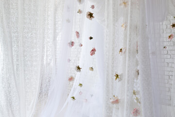 White lace texture curtains with floral abstract pattern with spring flowers levitate. Summer pink peonies flowers levitating, hanging flowers on a white background, copy space. Template, mockup. 
