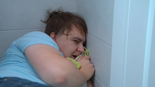 Frightened man hid from fear in the corner of room, hiding, panic attack, panic attack, paranoia An impressionable, emotional man watches a horror film, scary movie, reaction Victim of violence, abuse