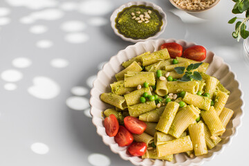 Delicious pasta with fresh basil pesto, green peas, cherry tomatoes and cheese.