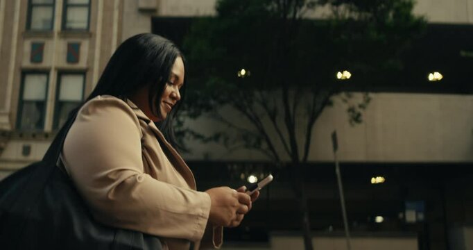 Young business woman walking around the city using her phone and laptop
