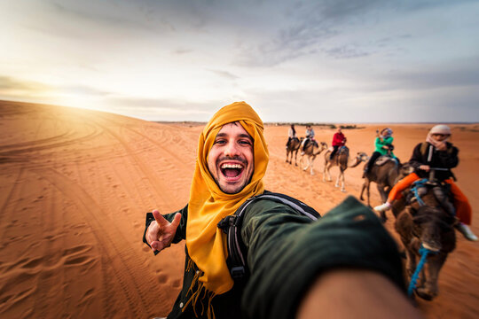 Happy tourist having fun enjoying group camel ride tour in the desert - Travel, life style, vacation activities and adventure concept