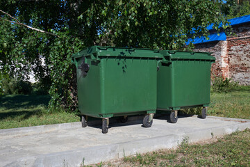 Two green trash cans on the street on a summer afternoon