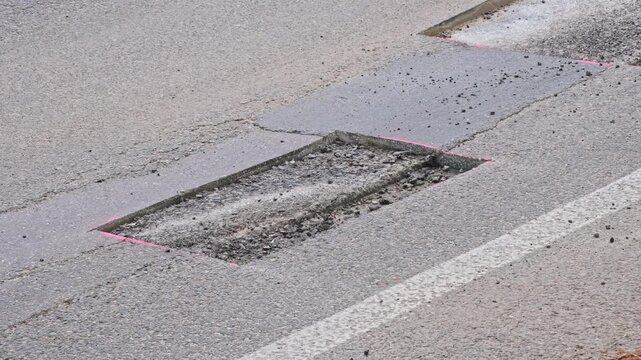 Car Driving over Cut Patch of Street Surface Asphalt Prepared for Roadworks Pothole Repair
