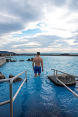 Fototapeta premium Man relaxing in the blue waters of a geothermal lagoon in Iceland