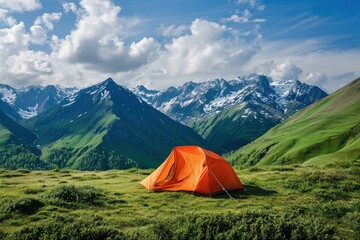 Orange tent stands in a lush green valley with striking mountain views under a clear sky