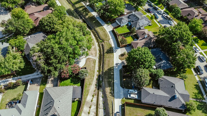 Upscale suburban houses with solar panel roofings along concrete channels facilitates drainage from residential street discharge into creek, flood storage capacity to waterway section, aerial