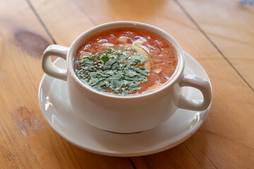 A white bowl of hot soup on a wooden table is a comforting and savory dish that is appetizing