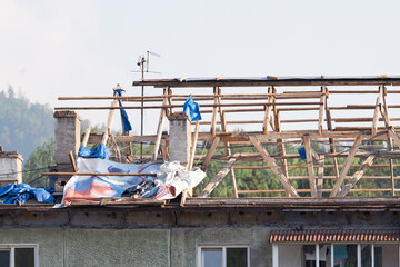Construction work in progress on a residential building with scaffolding and tarps on the rooftop
