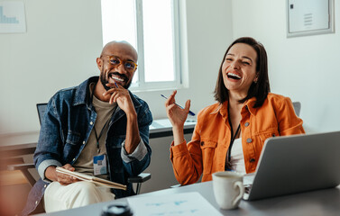 Smiling colleagues bonding and laughing during an office meeting in a casual setting