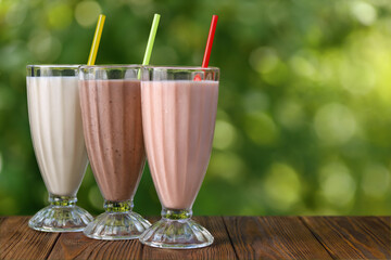 set of strawberry, vanilla and chocolate flavor milkshakes or smoothies on table outdoors