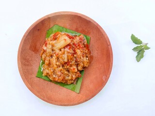 eggplant chili sauce, accompaniment to spicy food. fresh and hot traditional side dish. chili sauce made from eggplant served on a wooden plate against white background
