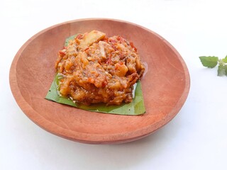 eggplant chili sauce, accompaniment to spicy food. fresh and hot traditional side dish. chili sauce made from eggplant served on a wooden plate against white background
