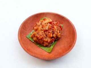 eggplant chili sauce, accompaniment to spicy food. fresh and hot traditional side dish. chili sauce made from eggplant served on a wooden plate against white background
