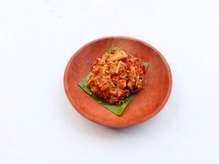eggplant chili sauce, accompaniment to spicy food. fresh and hot traditional side dish. chili sauce made from eggplant served on a wooden plate against white background
