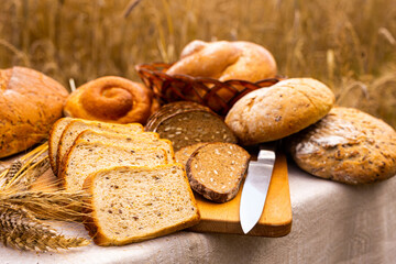 Lot of different flavored bread, wheat, rye, on the table in the field outside