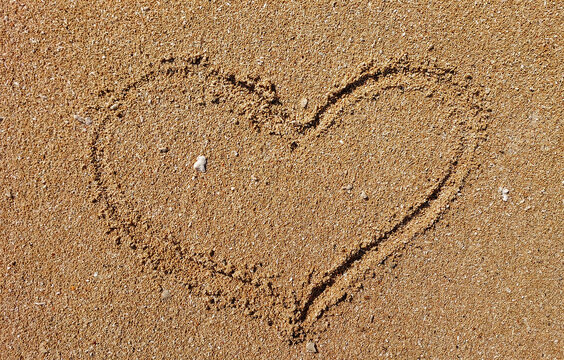 heart drawn or love sign on the sand beach