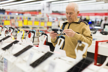 Senor man pensioner buying modern tablet digital in showroom of digital electronic goods store