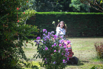 Beautiful young girl enjoying mowing the lawn with a tractor.