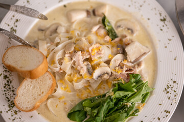 a bowl of creamy pasta with slices of mushrooms and shredded cheese
