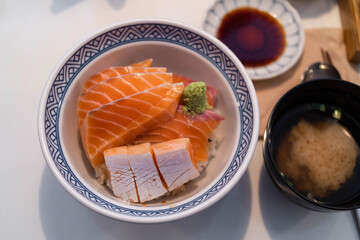 a bowl of sushi rice topped with fresh slices of salmon sashimi