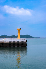 a bright yellow lighthouse on a concrete pier