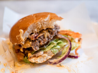 a burger with layers of lettuce, tomato, beef patty, cheese, and onions