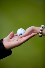Couple exchanging engagement ring and golf ball, symbolizing love and commitment.