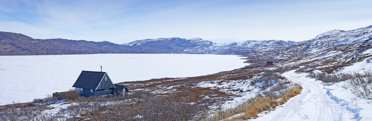 Landscape, road and mountains in snow, building or house in Kangerlussuaq, Greenland, Denmark. Winter, ice and highway by hill for infrastructure with horizon, travel or path with lake in environment © Dhoxax/peopleimages.com