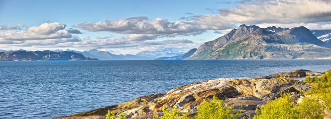 Coast, mountain and ocean with view of nature in Norway for horizon, sustainability or travel. Clouds, earth and environment with natural terrain in Europe for conservation, holiday or vacation
