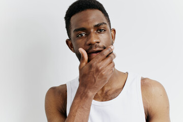 Contemplative african american man in white tank top holding hand to mouth in thoughtful expression