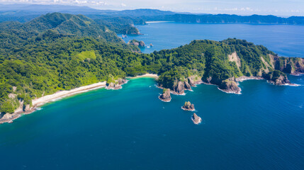 Aerial view of lush green tropical coastline with turquoise waters and rocky outcrops in a pristine, serene bay