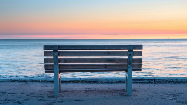 Empty wooden park bench facing calm ocean with sunset, symbolizing retirement and peaceful future planning.