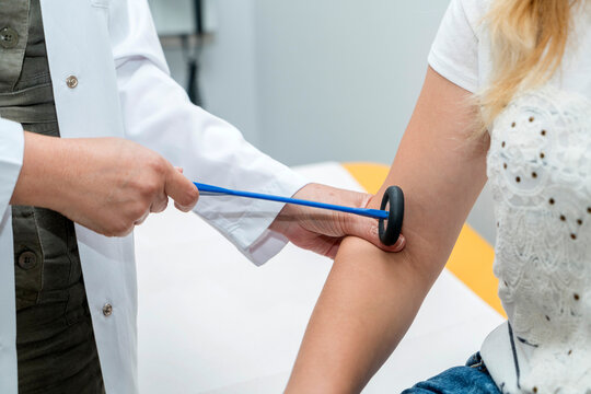 The neurologist testing elbow reflex on a man patient using a hammer. Neurological physical examination. Orthopedist work. Orthopedic surgeon examining checks the physiological reflex test hammer.