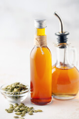 Pumpkin oil and seeds in bottles on a bright background.