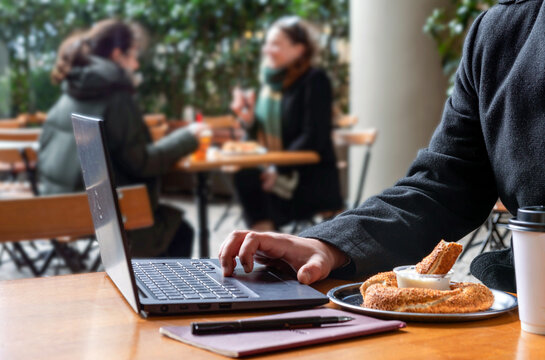 business man working on a laptop in cafe. employee working on the table with snacks. man using laptop computer with cup coffee and bread on the table, Looking for direction and inspiration. - Powered by Adobe