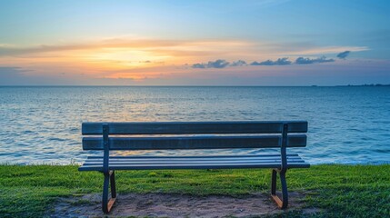 Empty wooden park bench facing calm ocean with sunset, symbolizing retirement and peaceful future planning.