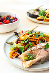 Baked silver carp with roasted carrots, zucchini, beets, and garlic, accompanied by fresh seasonal...