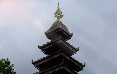 Fototapeta premium A multi-tiered dark brown wooden roof with a pointed yellow peak. Rays of light from the sun shine down.