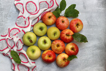 Fresh red and yellow apples with leaves on grey background, top view