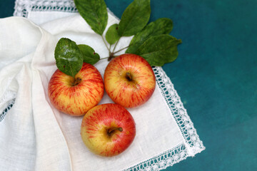 Apples on a white napkin on a turquoise background with space for text. Simple composition still life with red apple. 
