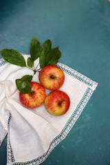 Apples on a white napkin on a turquoise background with space for text. Simple composition still life with red apple. 