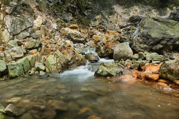 Naklejka premium Rushing Waters Over Vibrant Rocks