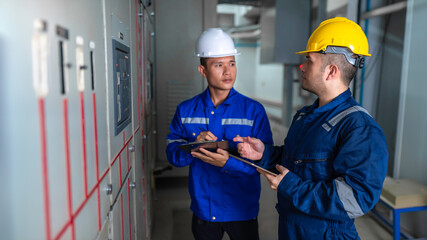 Electrical engineers and technicians work together to solve electrical system failures in industrial control rooms.supervisor maintains the circuit cabinet.