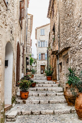 Obraz premium Charming Stone Pathway with Potted Plants and Historic Buildings in Quaint Village