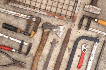 Old construction tools laid out on a concrete background, top view. Hammer, construction clamp,...