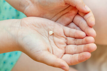 Child is holding a fallen milk tooth in his hands, close-up. Growing up children, pediatric dentistry, changing baby teeth to permanent concept.