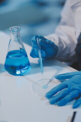 Group of dedicated scientist conduct chemical experiment in medical laboratory, carefully drop precise amount of liquid from pipette into test tube for vaccine drug or antibiotic development. Neoteric