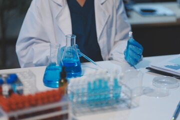 Fototapeta premium Group of dedicated scientist conduct chemical experiment in medical laboratory, carefully drop precise amount of liquid from pipette into test tube for vaccine drug or antibiotic development. Neoteric