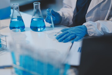 Fototapeta premium Group of dedicated scientist conduct chemical experiment in medical laboratory, carefully drop precise amount of liquid from pipette into test tube for vaccine drug or antibiotic development. Neoteric